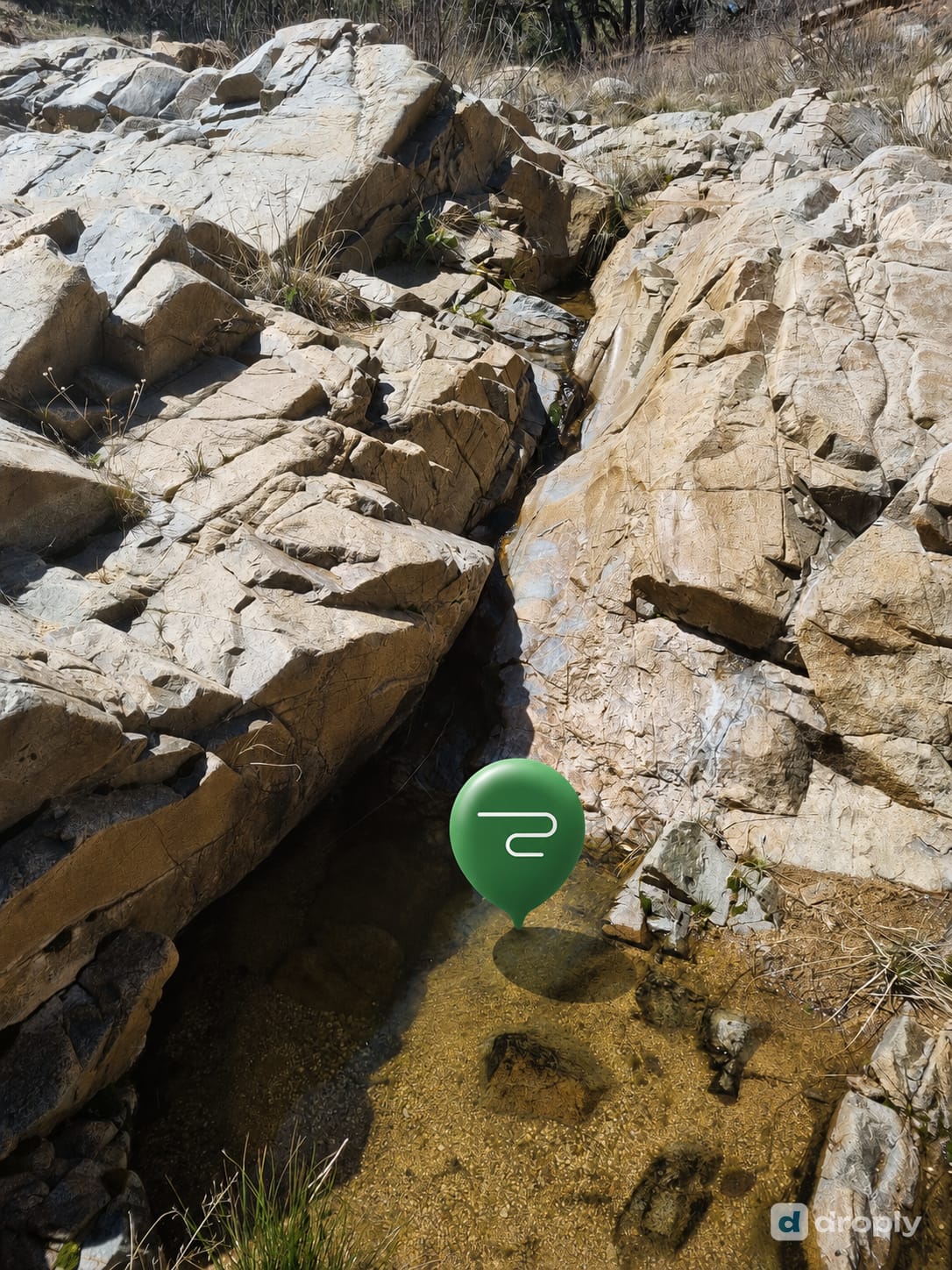 droply map marker over a small spring flowing between sun-bleached rocks