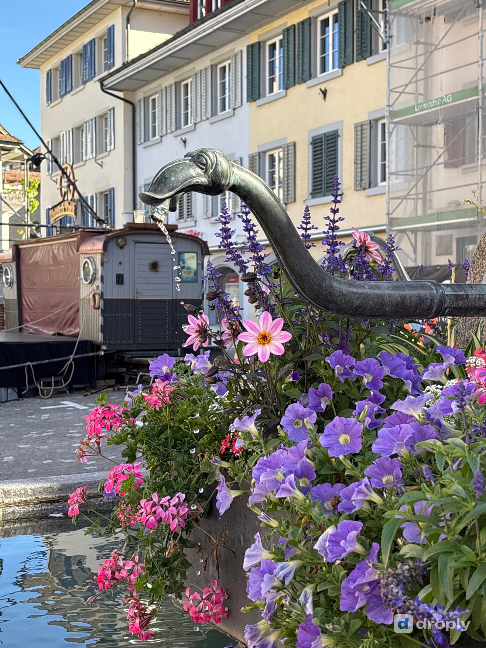 An ornate bronze fountain flowing among flowers in the old town of Sursee, Switzerland