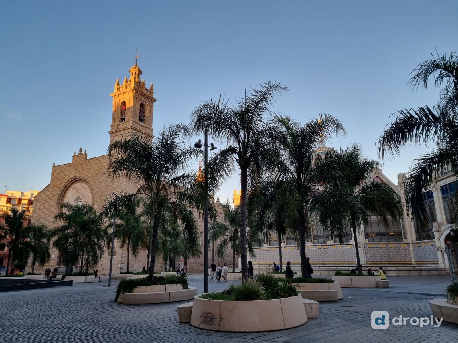 The church of Sant Joan del Mercat and the Mercat Central in Valencia's old town at sunset, with palm trees on the square in front