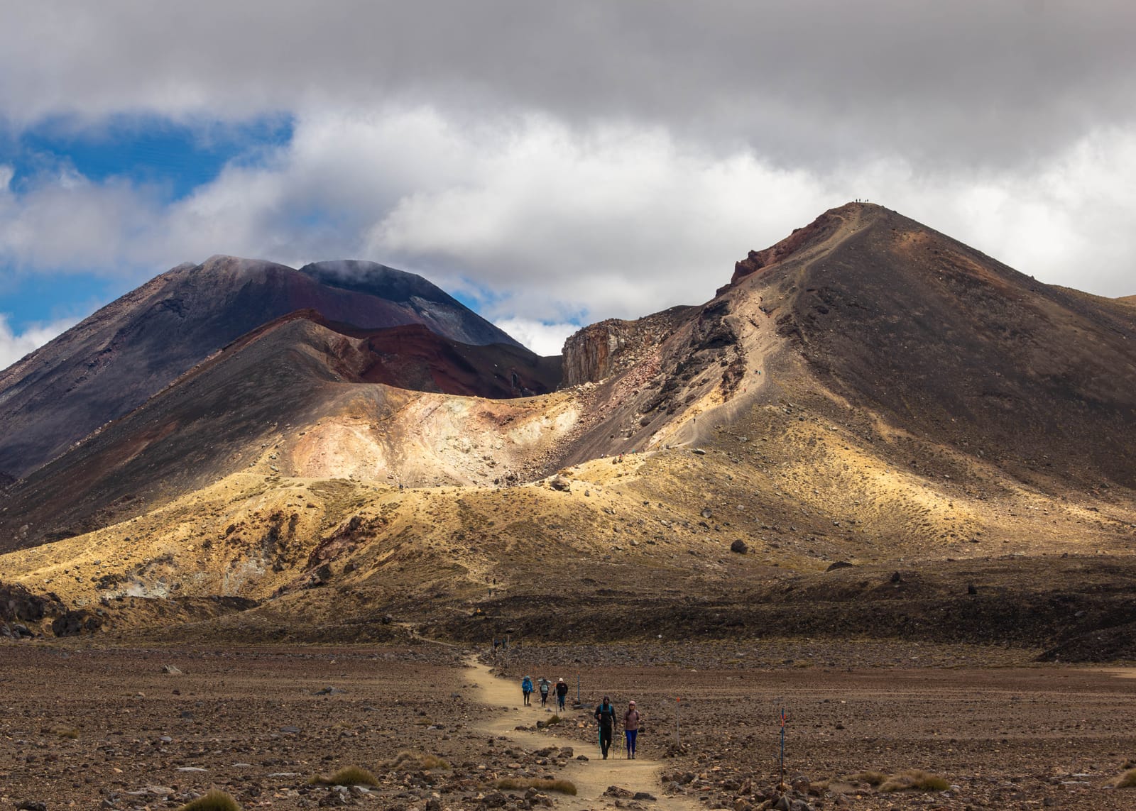 Hikers crossing the volcanic alpine terrain of the Tongariro Alpine Crossing in New Zealand