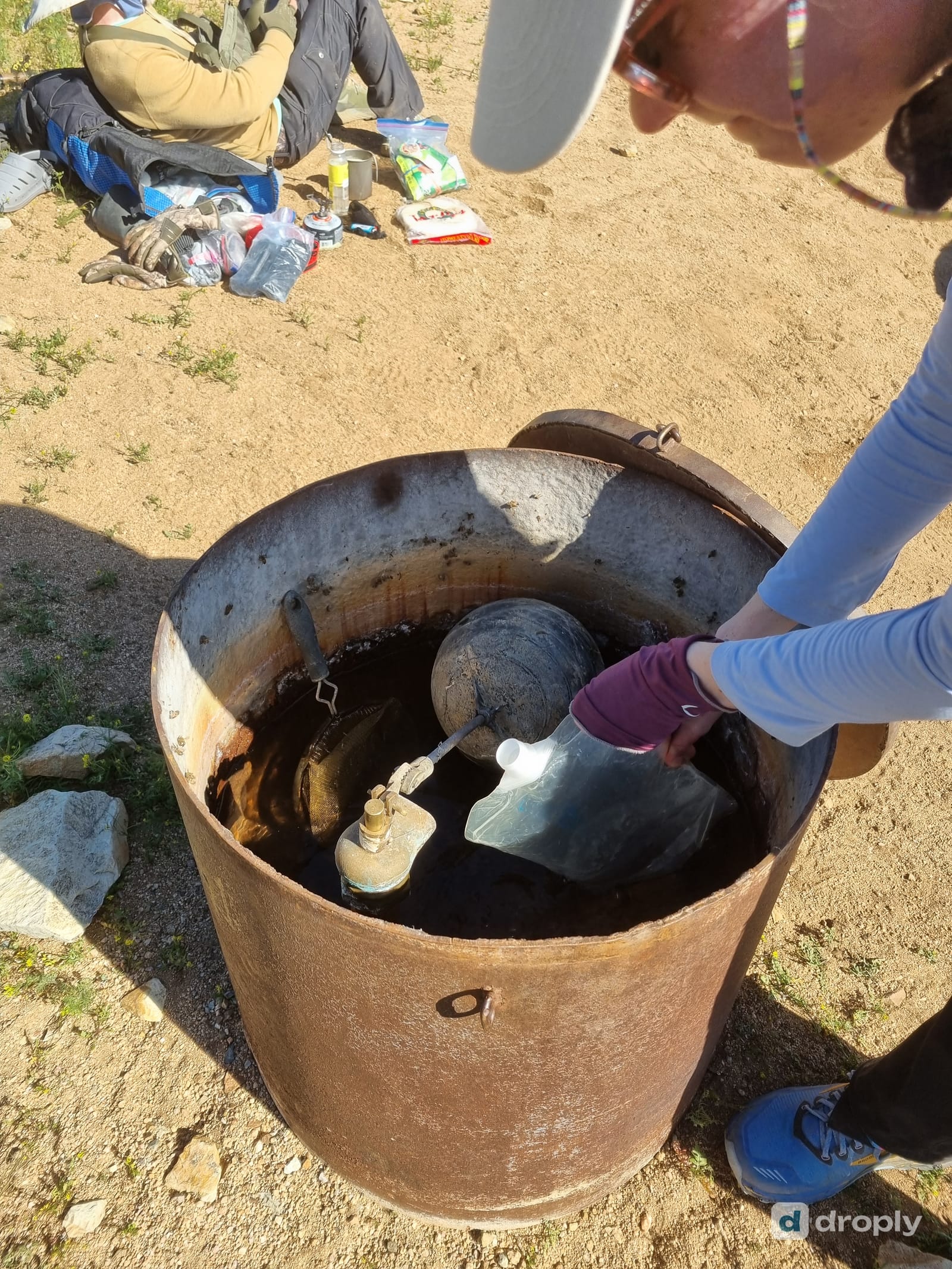 Filling a water bottle from a rusty cattle water tank in the New Mexico desert
